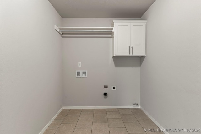 washroom with electric dryer hookup, cabinets, light tile patterned floors, and hookup for a washing machine