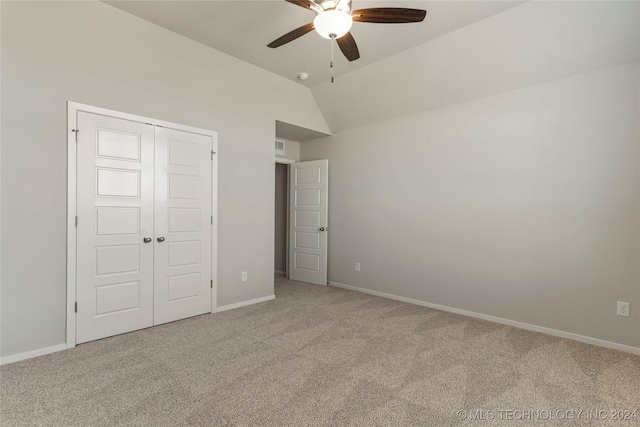 unfurnished bedroom featuring carpet, a closet, vaulted ceiling, and ceiling fan