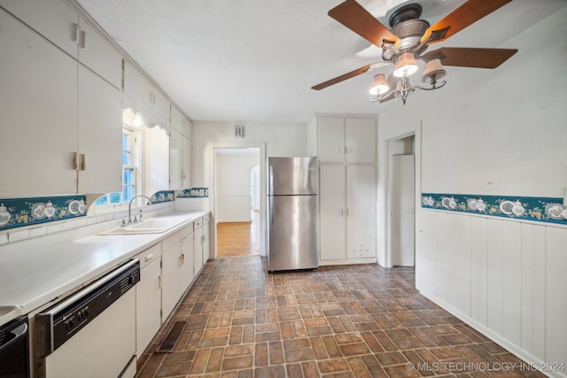 kitchen with white dishwasher, white cabinetry, sink, and stainless steel refrigerator