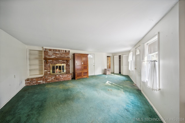 unfurnished living room featuring built in shelves, dark carpet, and a brick fireplace