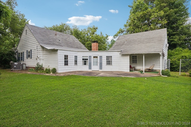 rear view of house with a patio, central air condition unit, and a lawn