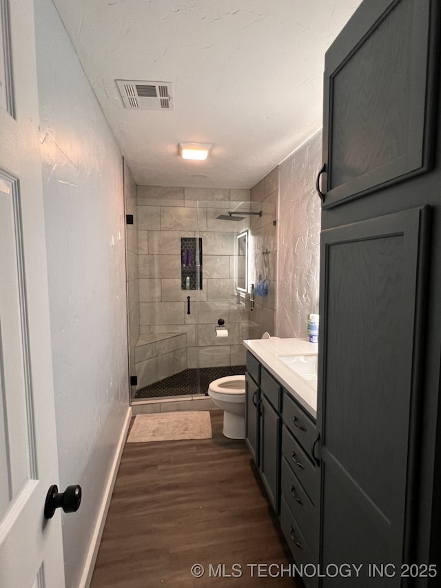 bathroom with an enclosed shower, vanity, toilet, and wood-type flooring