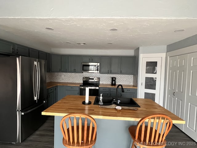 kitchen featuring wooden counters, backsplash, stainless steel appliances, and sink