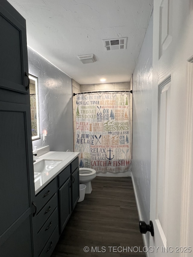 full bathroom featuring hardwood / wood-style flooring, vanity, shower / bath combination with curtain, and toilet