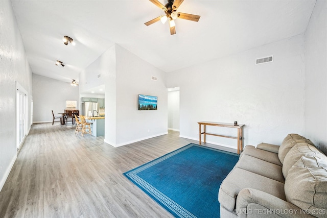 living room with ceiling fan, hardwood / wood-style floors, and high vaulted ceiling