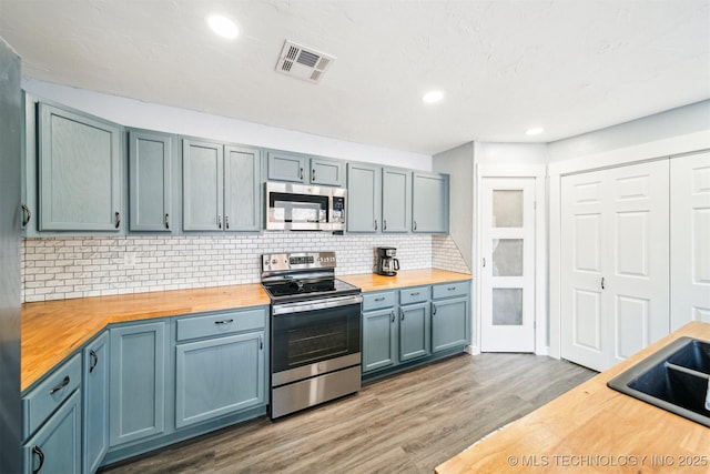 kitchen with dark hardwood / wood-style flooring, stainless steel appliances, tasteful backsplash, and butcher block counters