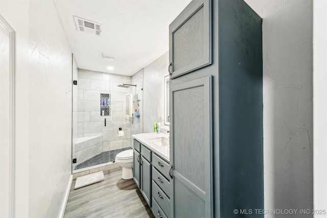 bathroom featuring wood-type flooring, vanity, toilet, and an enclosed shower