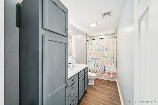 full bathroom with shower / bath combo with shower curtain, toilet, vanity, and hardwood / wood-style flooring