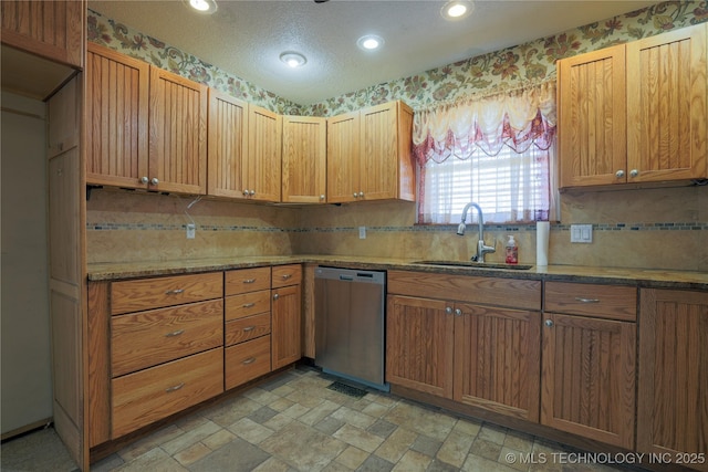 kitchen with dark stone counters, sink, stainless steel dishwasher, and a textured ceiling