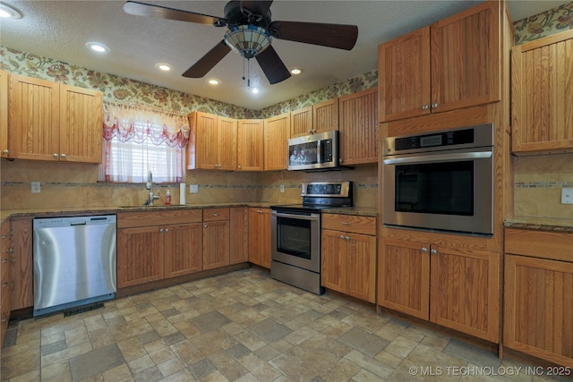 kitchen with a textured ceiling, ceiling fan, sink, and stainless steel appliances