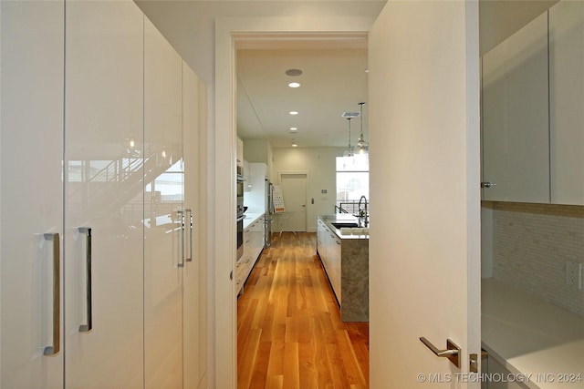 corridor with sink and light wood-type flooring