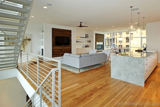 living room with hardwood / wood-style floors, ceiling fan, and sink