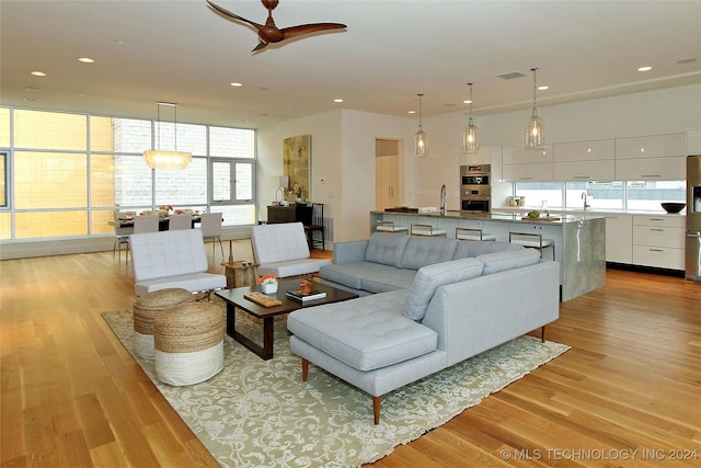 living room with ceiling fan, sink, a healthy amount of sunlight, and light wood-type flooring