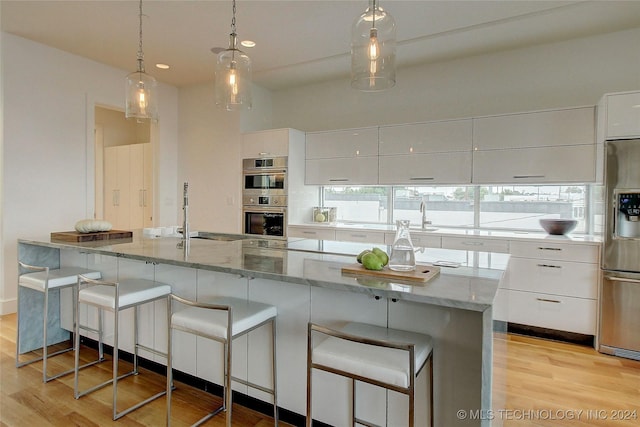 kitchen with a kitchen island with sink, white cabinets, and stainless steel appliances