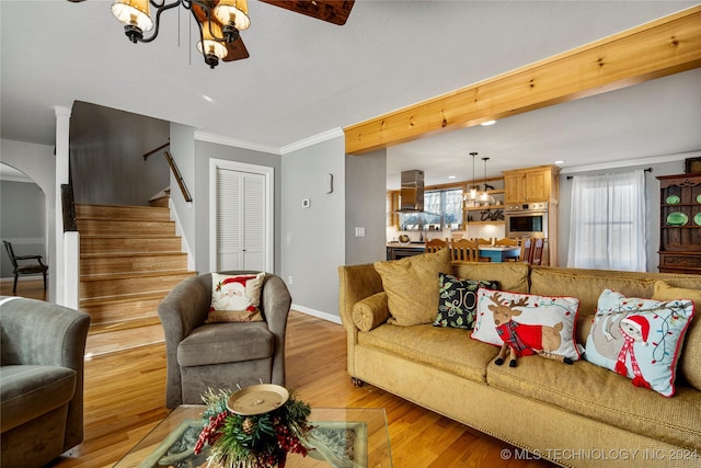 living room featuring light hardwood / wood-style floors, an inviting chandelier, and ornamental molding