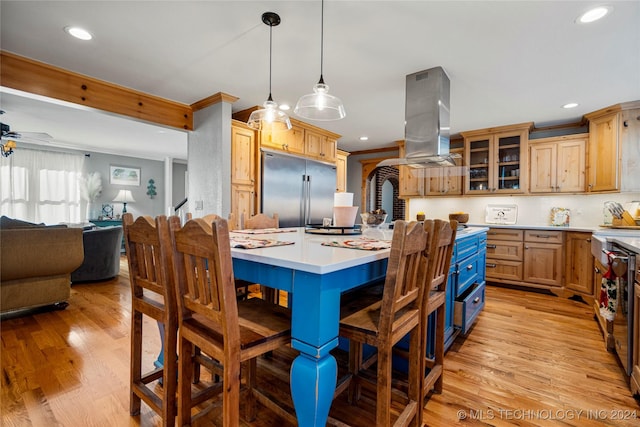 kitchen with a center island, built in fridge, light wood-type flooring, decorative light fixtures, and island range hood