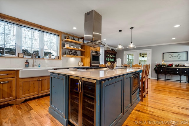 kitchen featuring island exhaust hood, sink, decorative light fixtures, a center island, and wine cooler