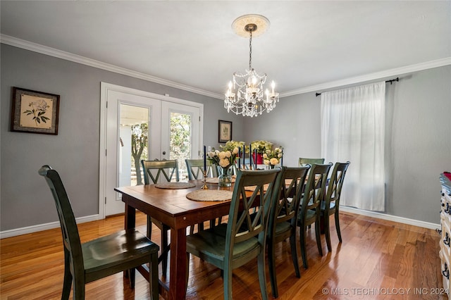 dining space featuring french doors, ornamental molding, a notable chandelier, and hardwood / wood-style flooring