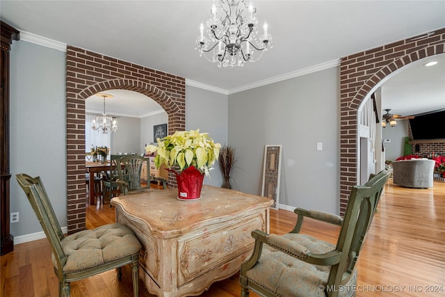 dining space featuring crown molding, brick wall, light hardwood / wood-style floors, and ceiling fan with notable chandelier