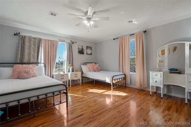 bedroom with multiple windows, wood-type flooring, ceiling fan, and ornamental molding