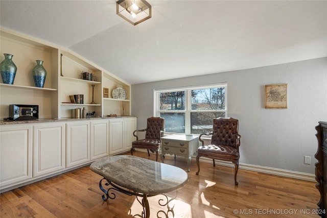 sitting room with built in shelves, vaulted ceiling, and light hardwood / wood-style flooring