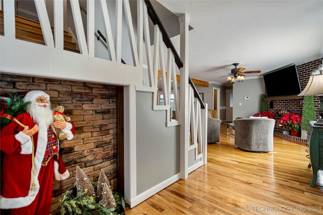 interior space featuring a brick fireplace, ceiling fan, crown molding, and brick wall