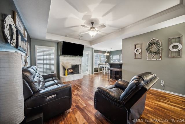 living room with ceiling fan, ornamental molding, dark wood-type flooring, and a tray ceiling