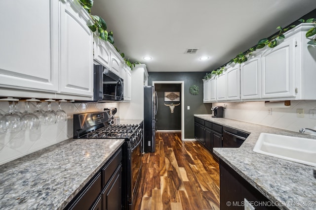 kitchen with light stone countertops, white cabinetry, sink, dark wood-type flooring, and black appliances