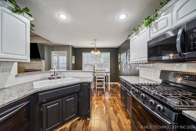 kitchen with white cabinetry, sink, black gas range oven, a notable chandelier, and decorative backsplash