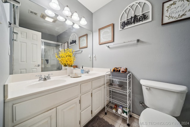 bathroom featuring tile patterned flooring, vanity, toilet, and a shower with door