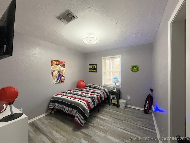 bedroom featuring a textured ceiling and hardwood / wood-style flooring