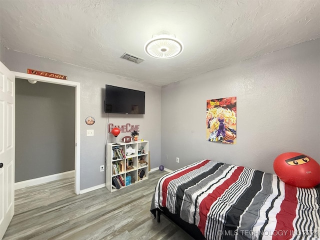 bedroom featuring wood-type flooring and a textured ceiling