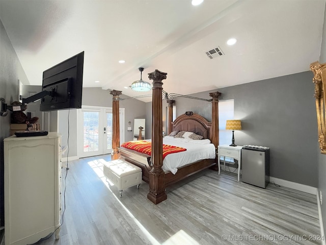 bedroom featuring decorative columns, vaulted ceiling with beams, light hardwood / wood-style flooring, and refrigerator