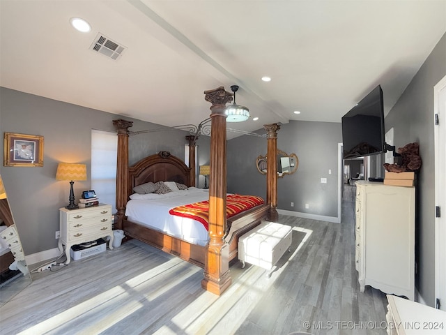 bedroom with hardwood / wood-style floors, ornate columns, and vaulted ceiling