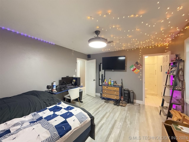 bedroom featuring connected bathroom and light hardwood / wood-style floors