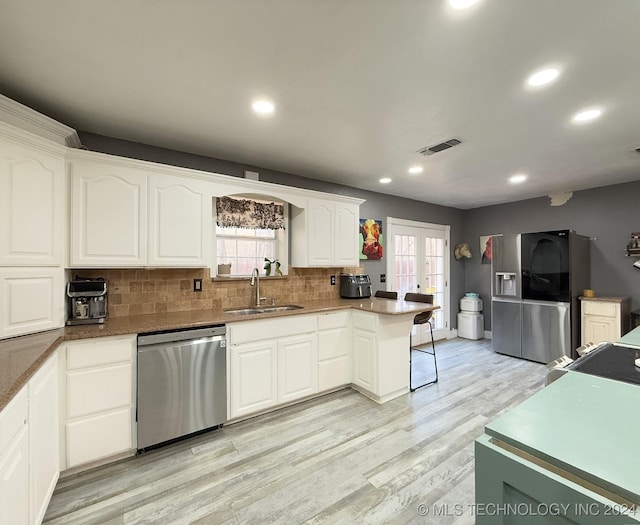 kitchen with white cabinetry, sink, french doors, light hardwood / wood-style flooring, and appliances with stainless steel finishes