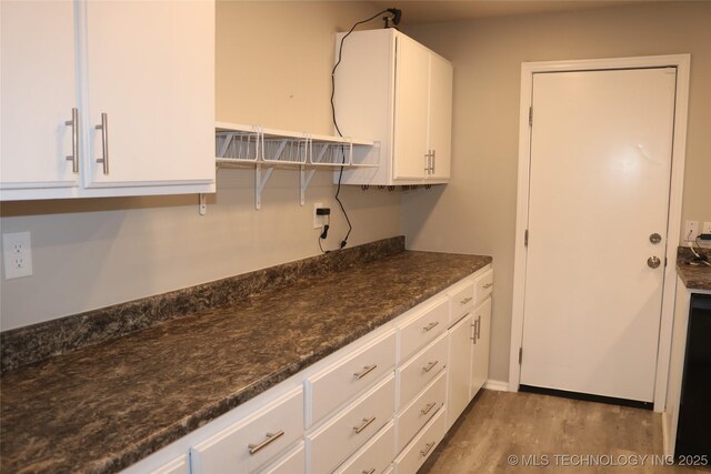 kitchen featuring white cabinets, light wood-type flooring, and dark stone counters