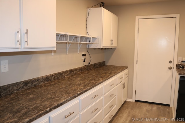 kitchen with dark stone countertops, white cabinets, and light wood-type flooring