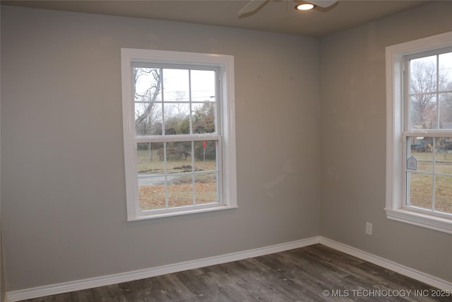 empty room featuring ceiling fan, a healthy amount of sunlight, and dark hardwood / wood-style flooring