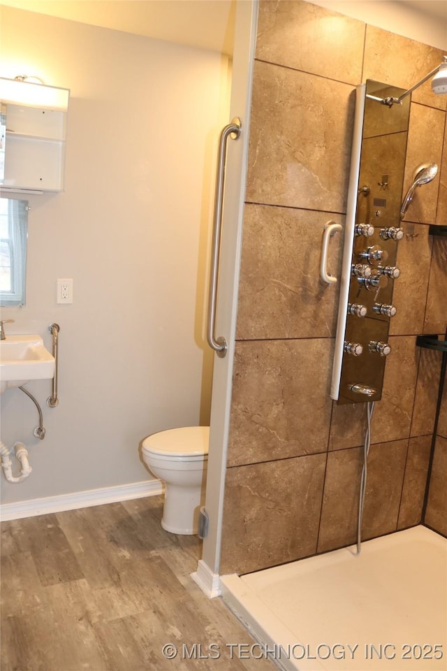 bathroom featuring a tile shower, hardwood / wood-style flooring, and toilet