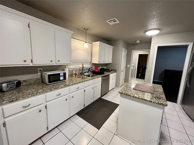 kitchen featuring sink, a textured ceiling, appliances with stainless steel finishes, a kitchen island, and white cabinetry