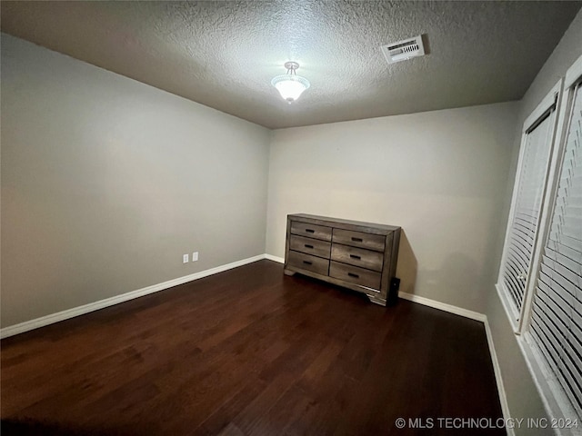 unfurnished bedroom featuring dark wood-type flooring and a textured ceiling