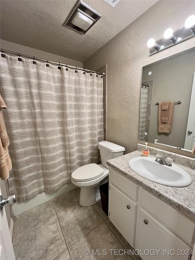 bathroom featuring tile patterned floors, vanity, a textured ceiling, and toilet