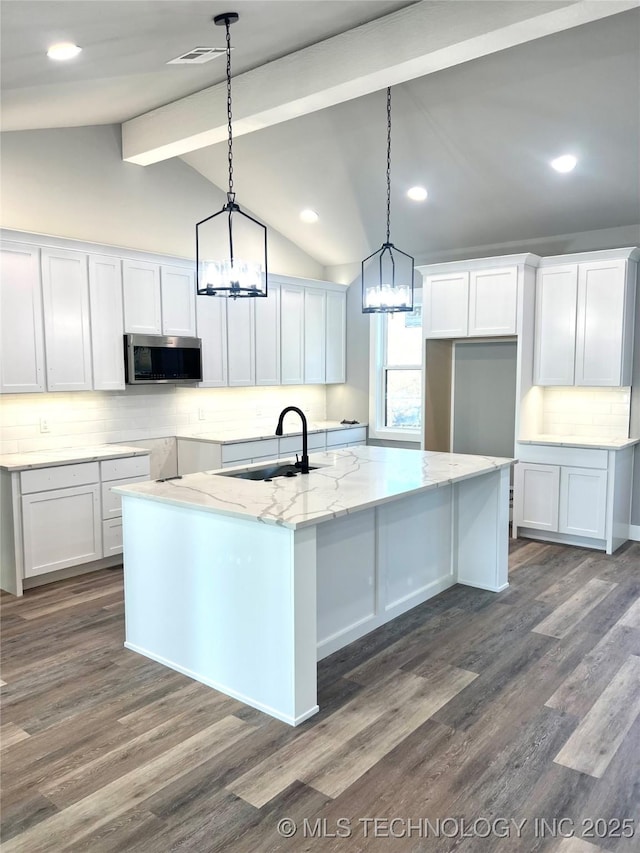 kitchen featuring backsplash, sink, pendant lighting, white cabinetry, and an island with sink