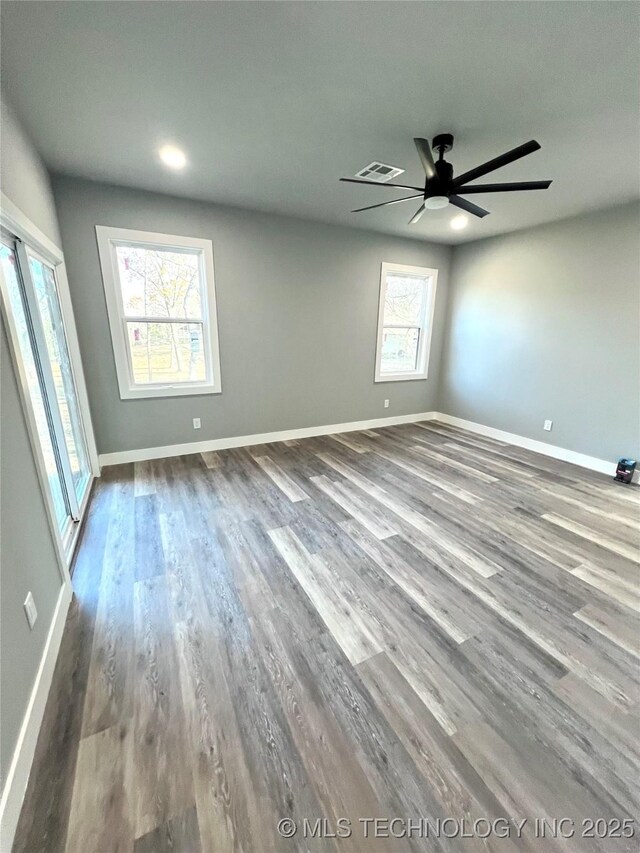 unfurnished room with wood-type flooring, a wealth of natural light, and ceiling fan