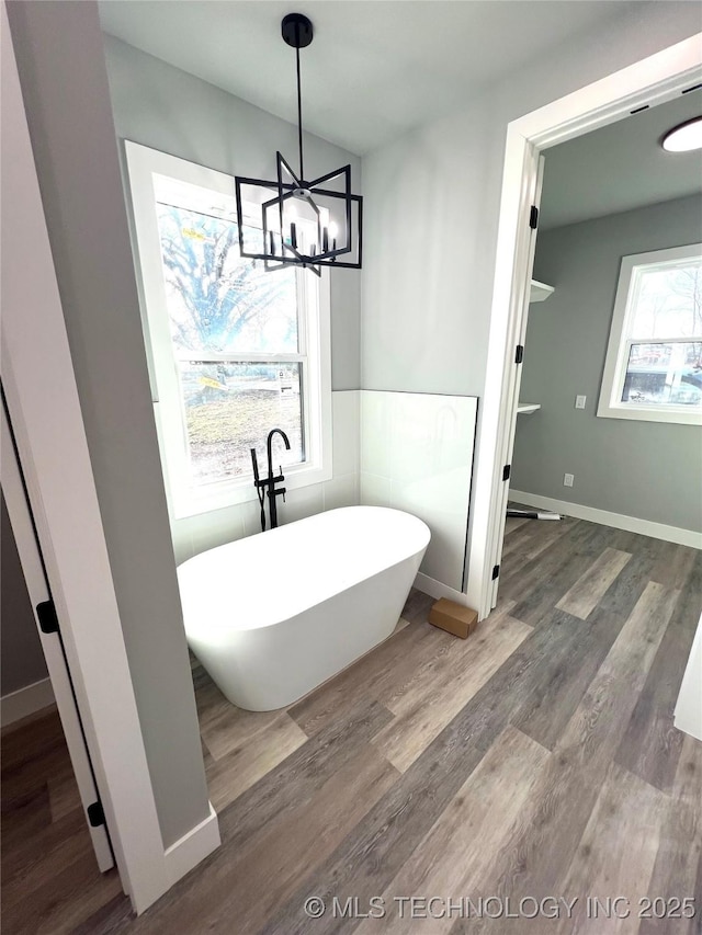 bathroom with a washtub, hardwood / wood-style floors, and a notable chandelier