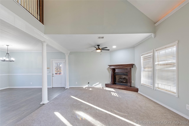 unfurnished living room with ceiling fan with notable chandelier, a healthy amount of sunlight, crown molding, and decorative columns