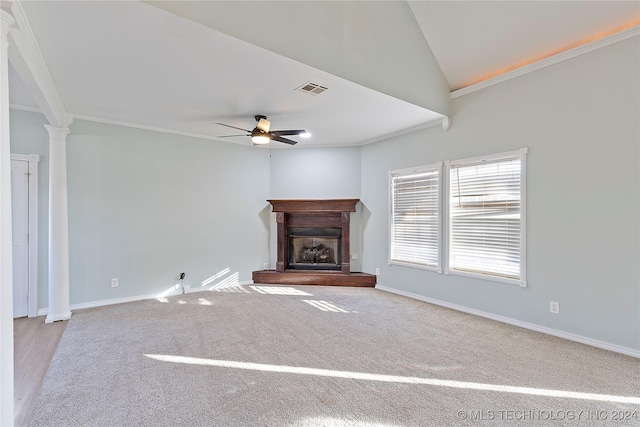 unfurnished living room featuring ornate columns, light colored carpet, vaulted ceiling, ceiling fan, and crown molding