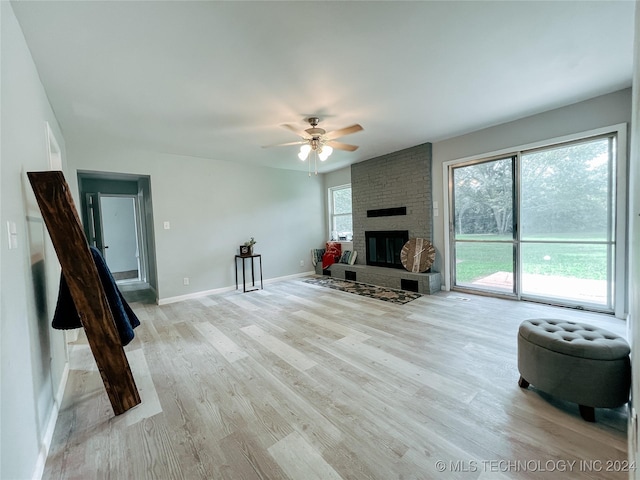 living room with ceiling fan, a fireplace, and light hardwood / wood-style flooring