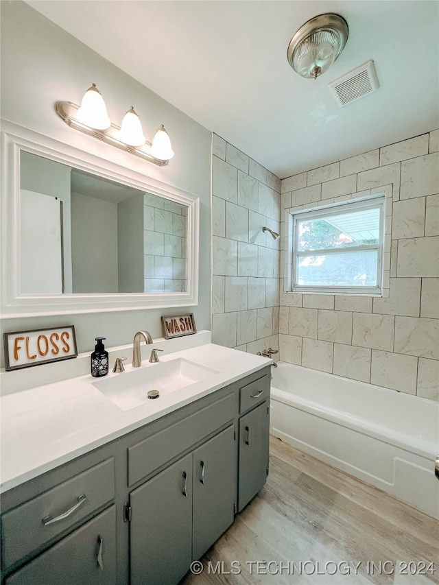 bathroom featuring hardwood / wood-style flooring, vanity, and tiled shower / bath